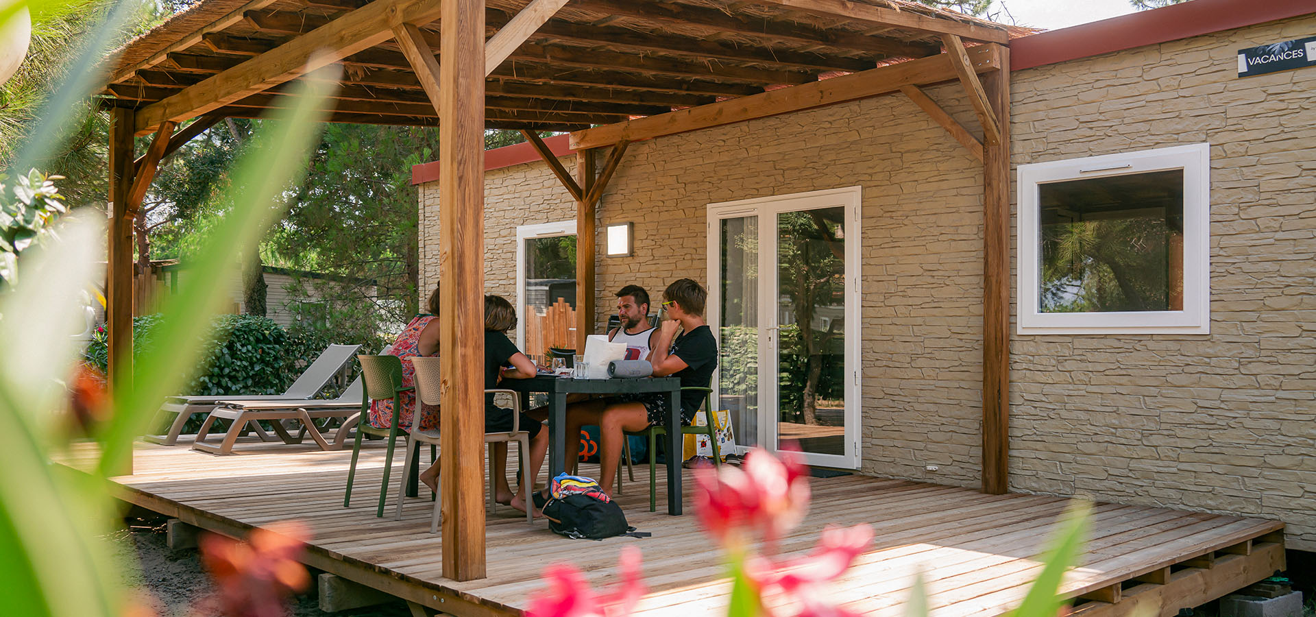 Camping san damiano bungalow montecristo vue terrasse avec famille a table