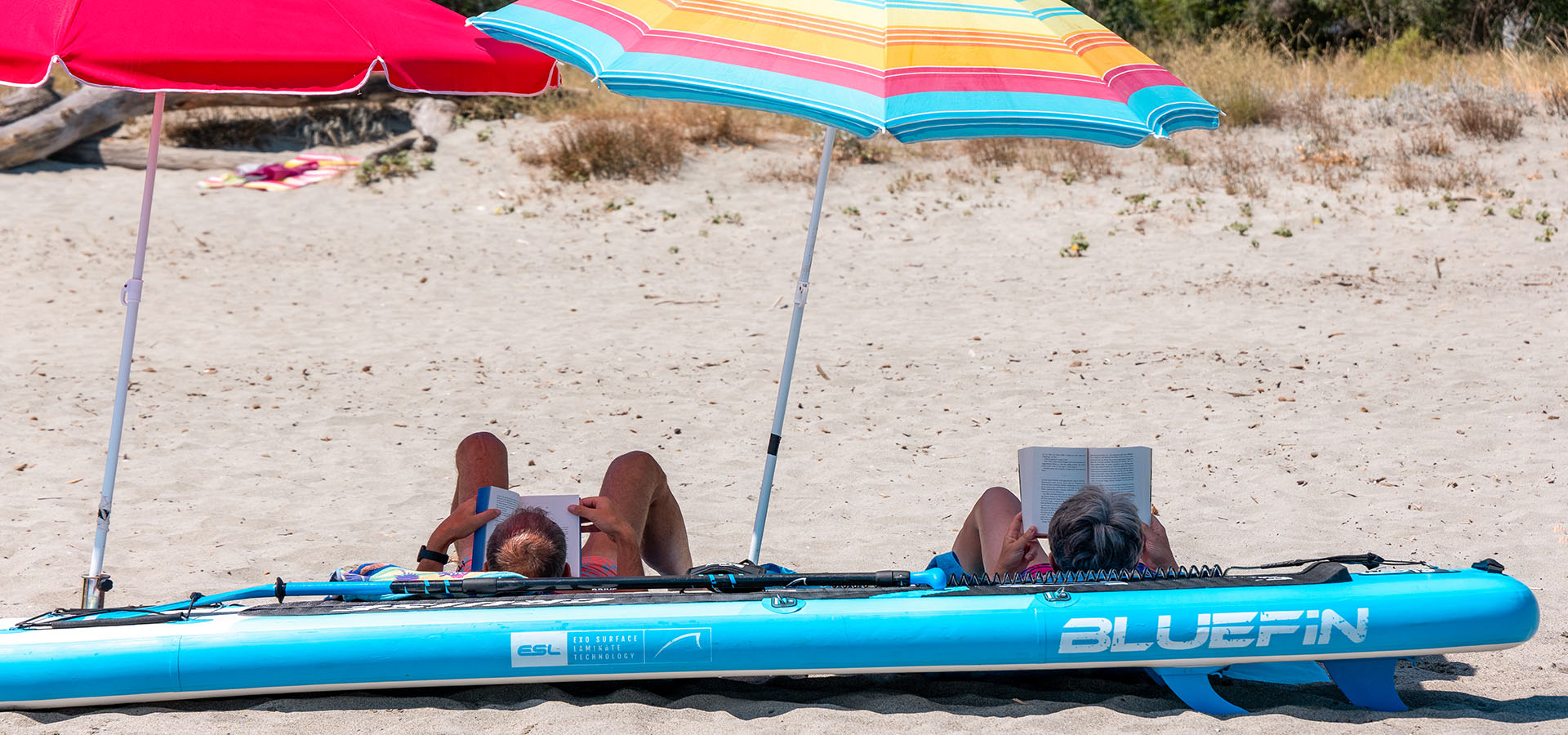 Camping san damiano plage couple qui lit planche de paddle